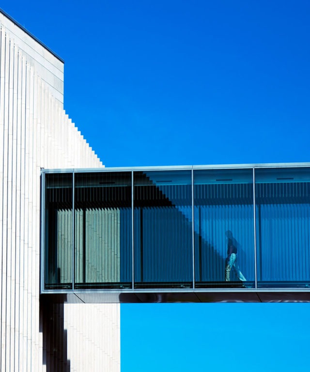 Exterior of a building walkway with windows and a person walking in it