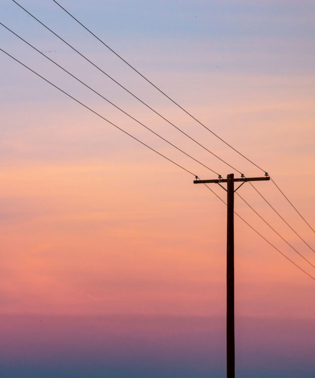 Overhead power lines with pink and purple skies in the background