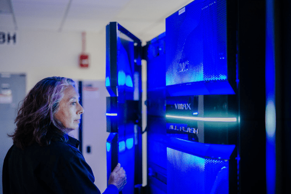 Women standing in front of mainframe system lit up in blue