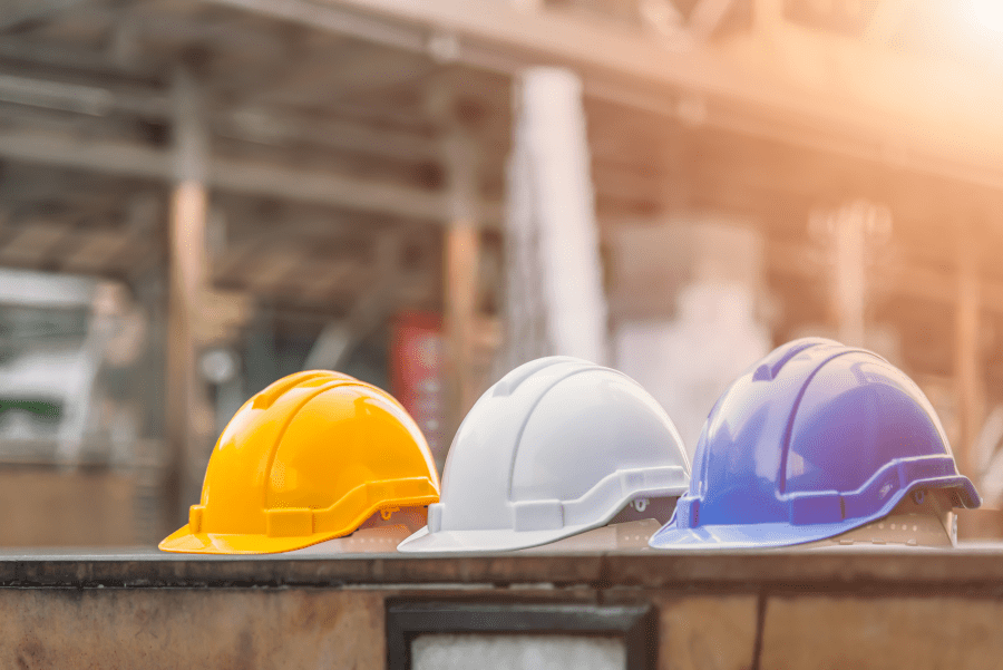 Yellow, white and blue hard hats neatly lined up at construction site.