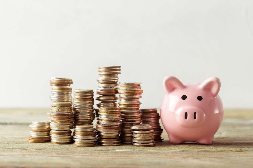 Multi-level stack of coins next to piggy bank