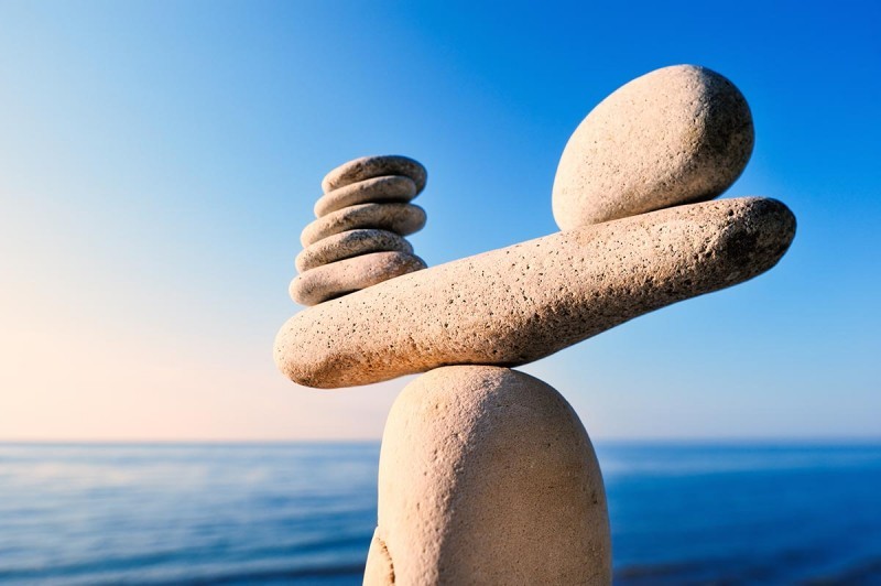 Multi-size rocks carefully balanced in front of water background 