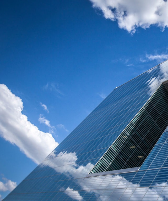 A partial view of the exterior of a building made of mirrored windows