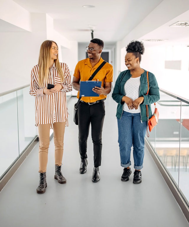 Three people walking down a hall together while talking