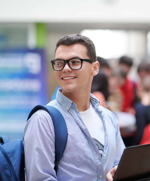 A man with glasses on looking over his shoulder and smiling