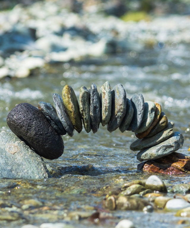 Small rocks stacked to create an arch in a creek