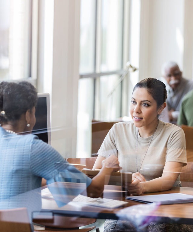 Two women sitting at a table across from each other having a discussion