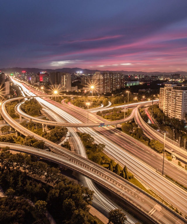 Overhead view of a city landscape, highways and several overpasses at night
