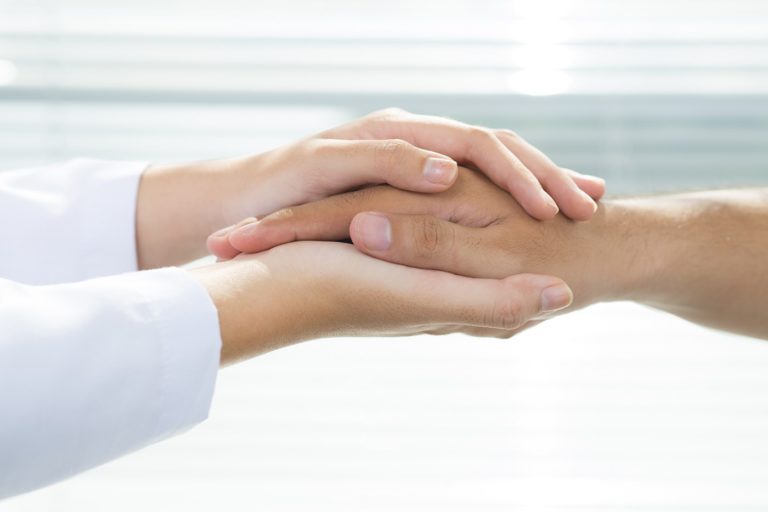 Two sets of hands embracing gently 