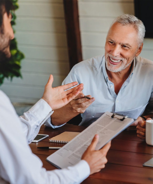 Two men talking over documents at table