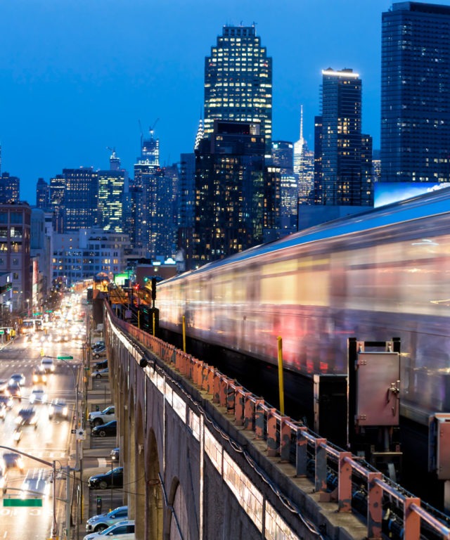 The side of a moving train with a cityscape in the background