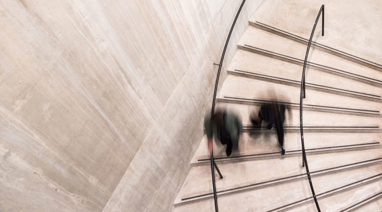 Bird's-eye view of two people going down a curved staircase