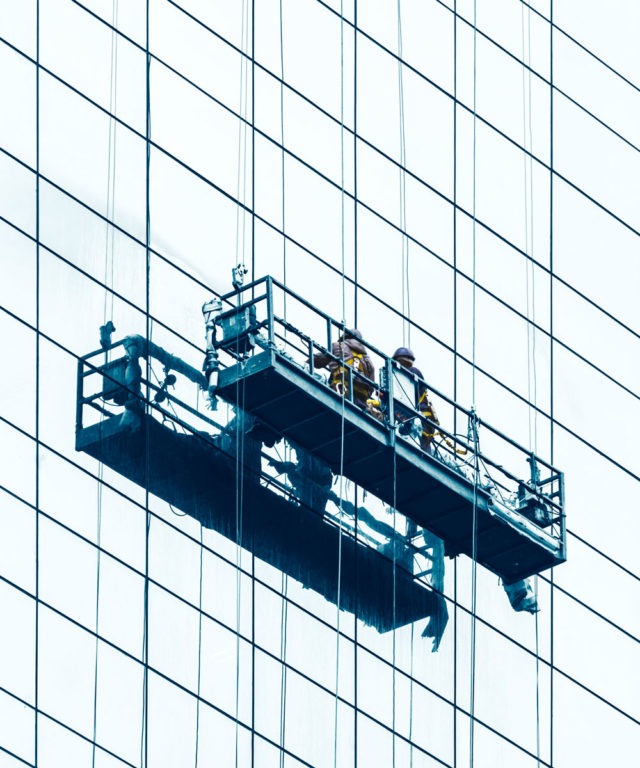 Two people suspended on the side of a skyscraper