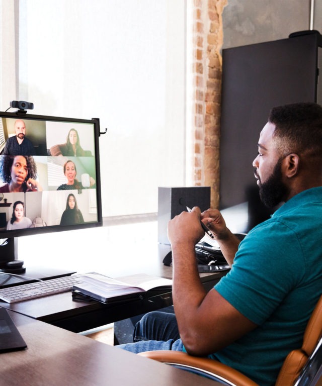 A man sitting at a desk looking at a computer screen for a video call