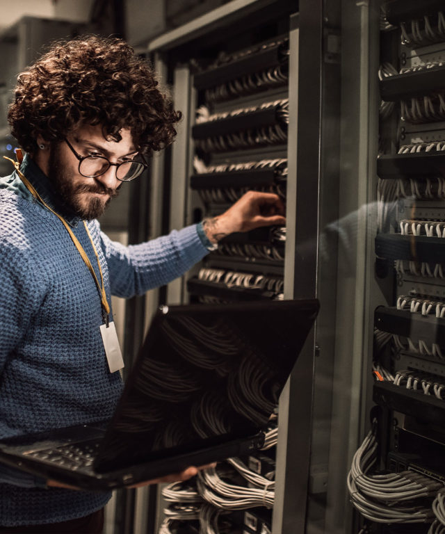 Man working on laptop in data center