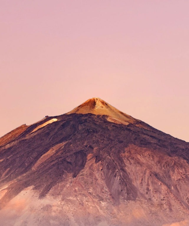 A mountain with pink skies in the background