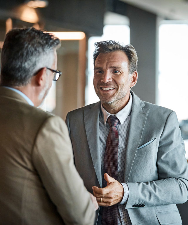 Two men in suits standing and talking to each other