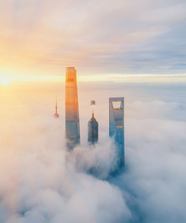 Three skyscrapers breaking through clouds