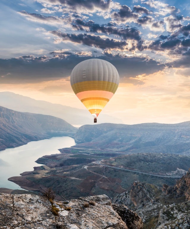 Hot air balloon flying above canyon and sunset