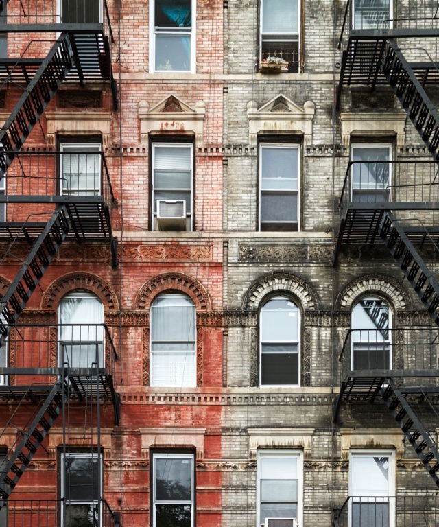 Fire escapes outside of red and gray brick buildings
