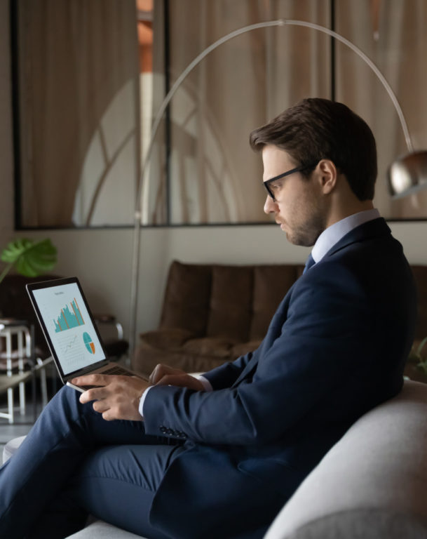 Businessman in formal suit viewing graphs on laptop