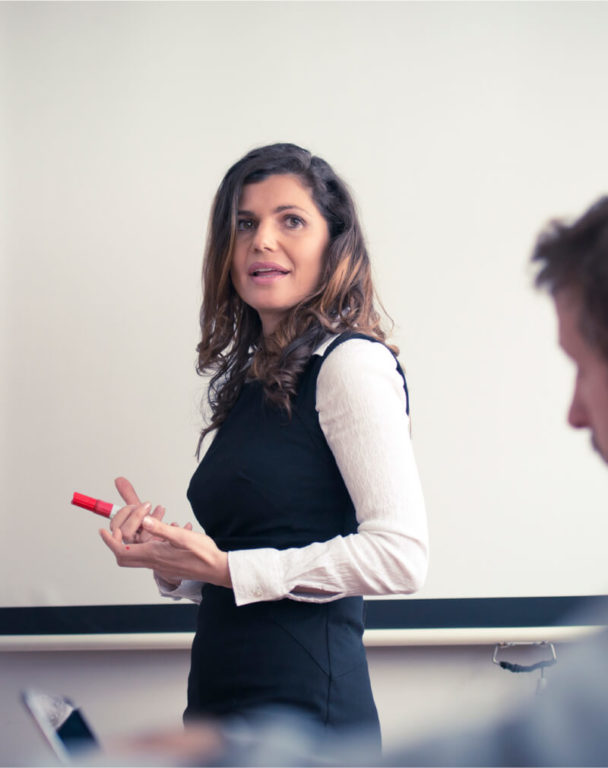 Woman working on a white board in front of a conference room