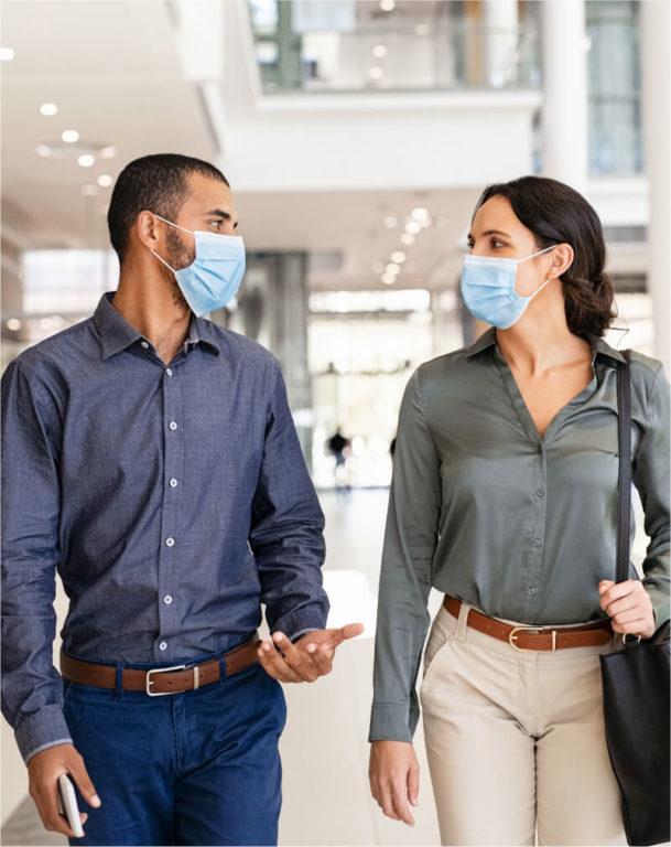 Business people in masks walking down an office hallway