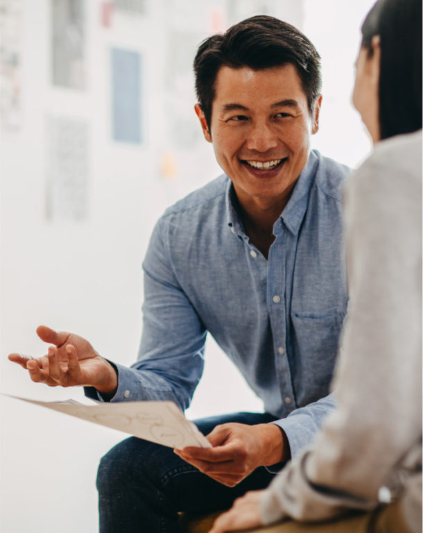 Man holding paper smiling with woman in modern office