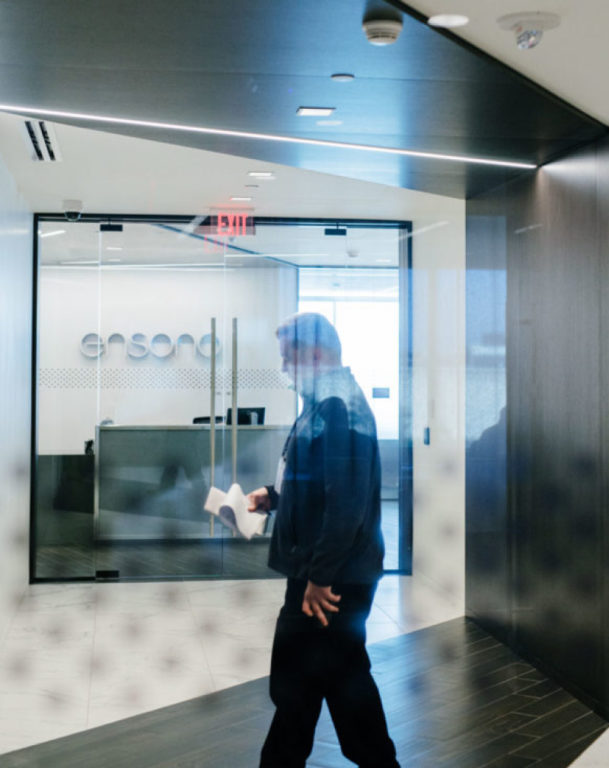 Man walking while using notepad in Ensono office