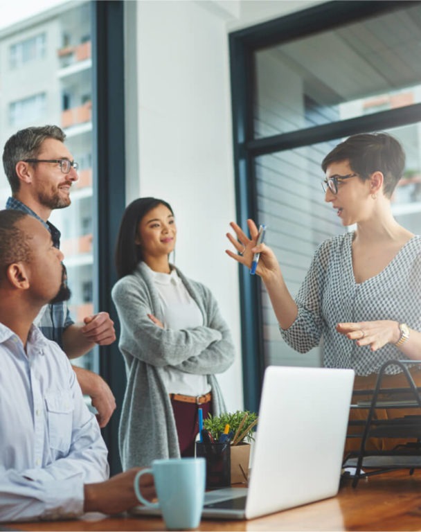 Four coworkers standing and talking in an office