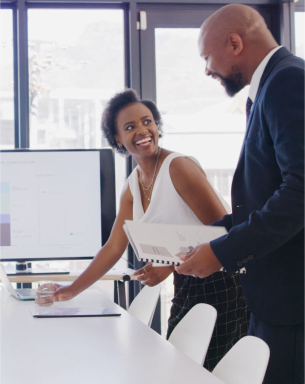 Two coworkers talking and leaning over a desk