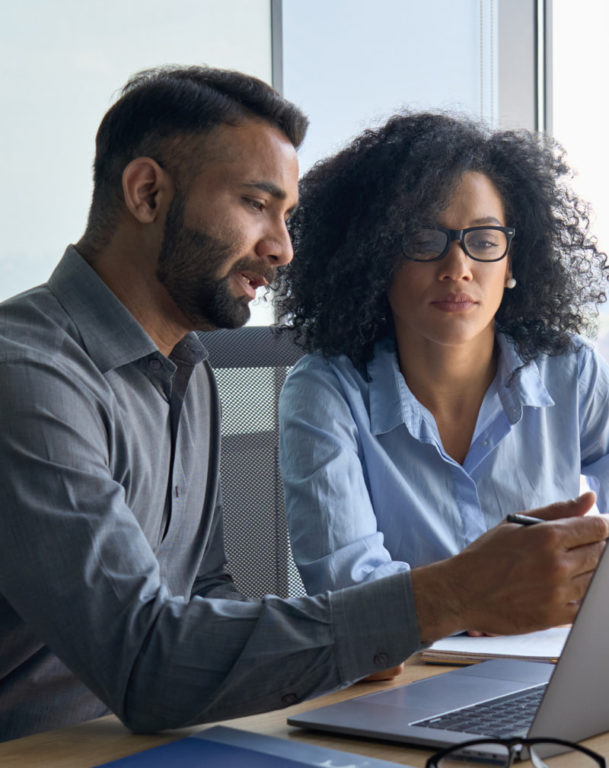 Man and woman sitting next to each other in front of laptop
