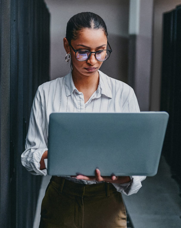 IT woman holding laptop in server room