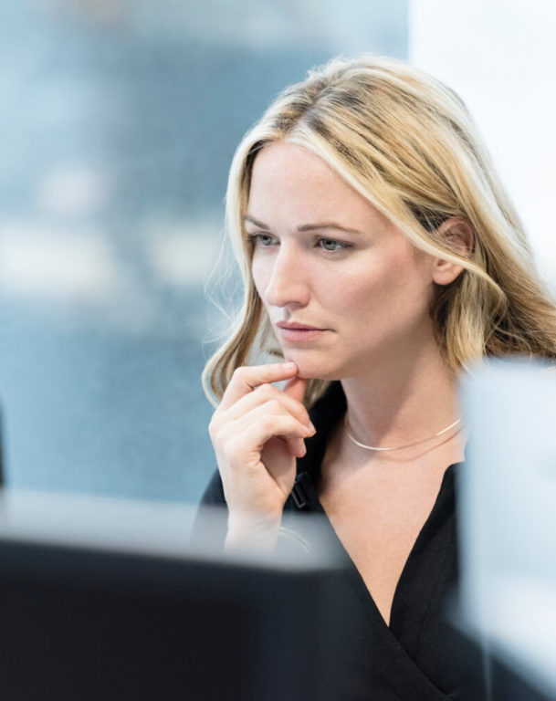 Woman in deep thought looking at desktop monitor