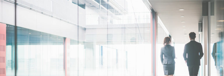 Two coworkers walking down hallway in office