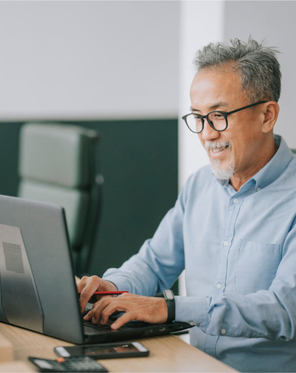Man smiling at a laptop in an office
