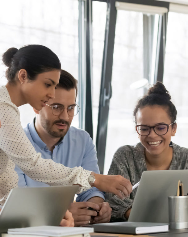 A group of young coworkers brainstorming in front of two laptops