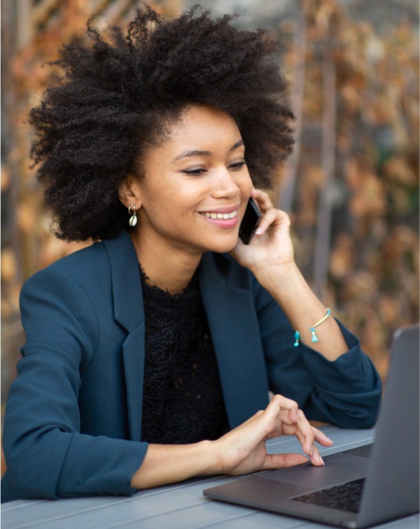 Smiling businesswoman on laptop while talking on cellphone