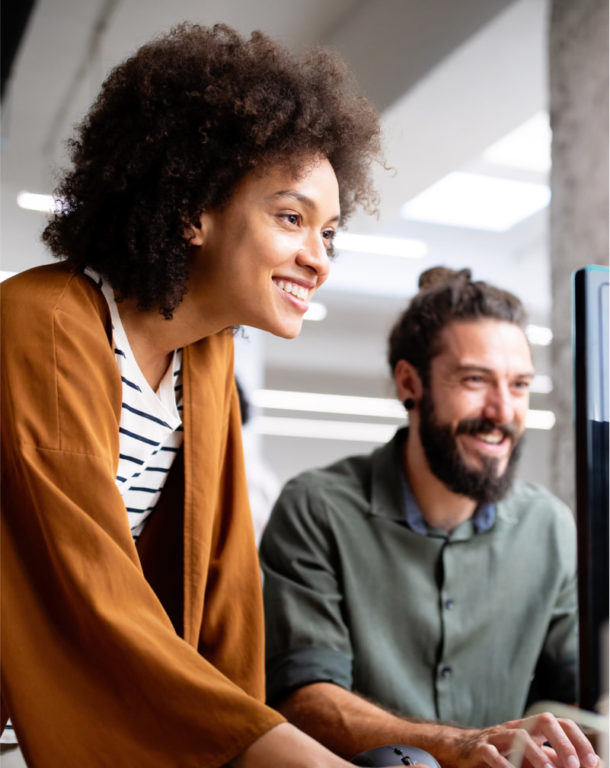 Two coworkers smiling in front of desktop