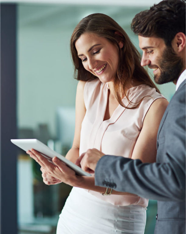 Smiling man scrolling on a tablet a woman is holding in an office