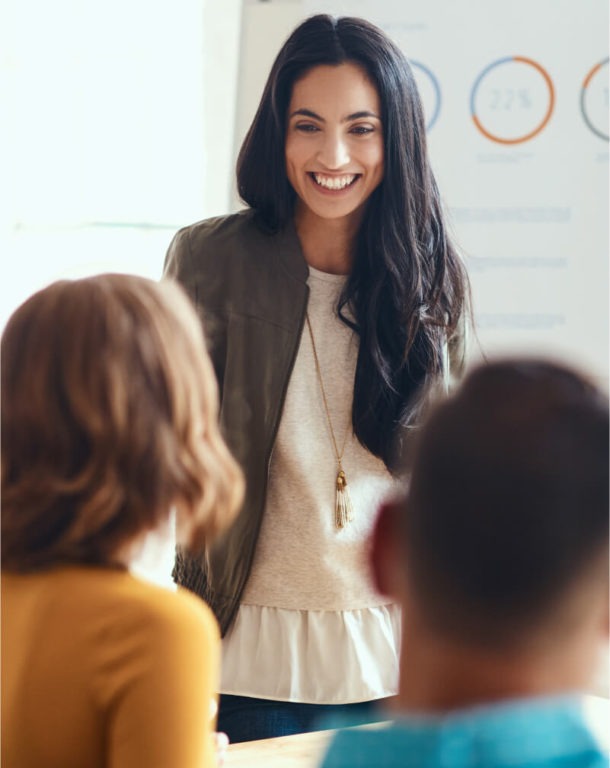 Female presenter smiling in front of colleagues in office