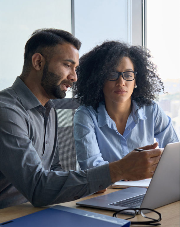 Man and woman sitting next to each other in front of laptop