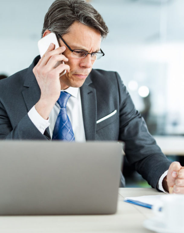 Man using the phone and looking at his computer