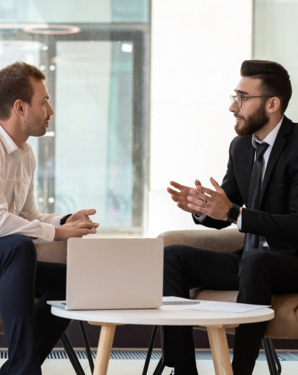 Two businessmen in armchairs having a discussion