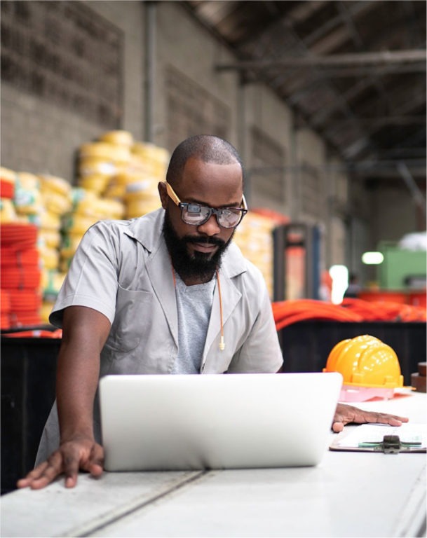 Man in warehouse viewing laptop at table