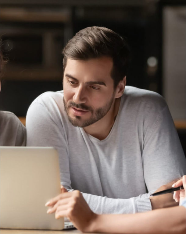 Three coworkers sitting at a table looking at a laptop