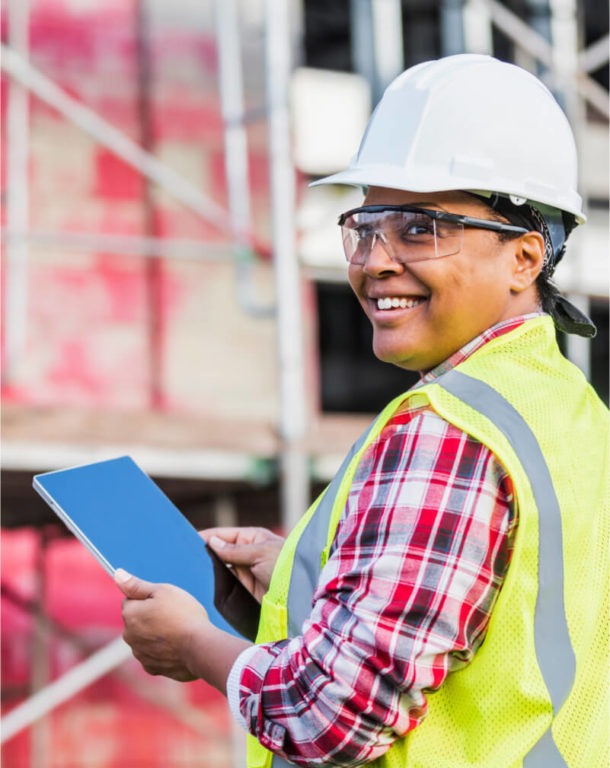 Woman in hard hat and vest working in manufacturing plant
