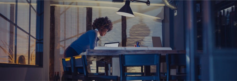 Woman leaning over a desk working in a dark office