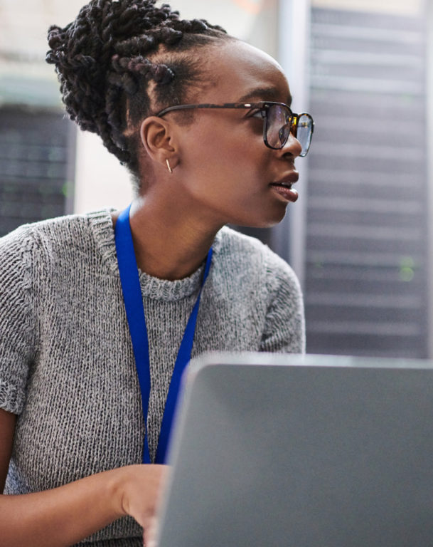 Young woman on laptop in server room