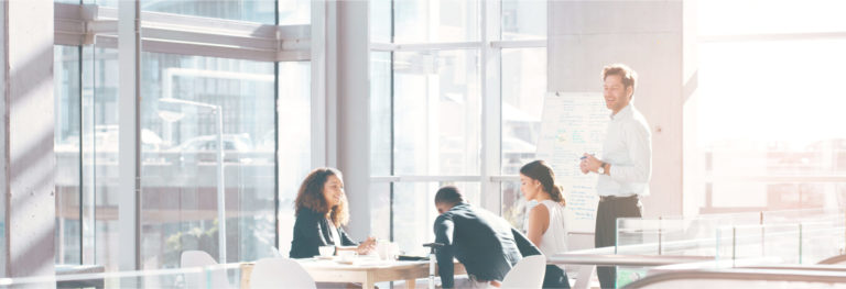 Four coworkers working at a conference table in a bright office